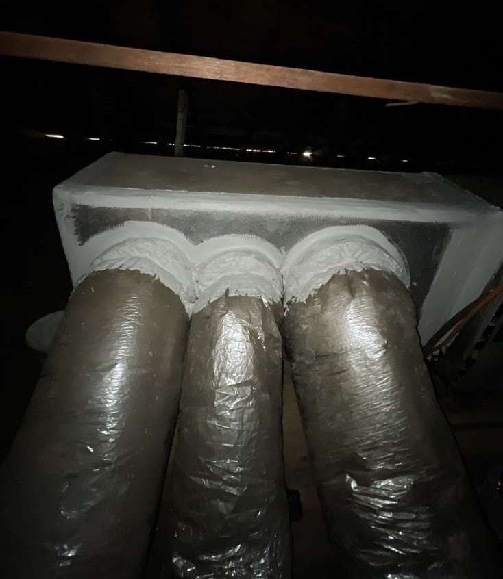 Sheet-metal plenum with three flex ducts joined and freshly sealed with white mastic