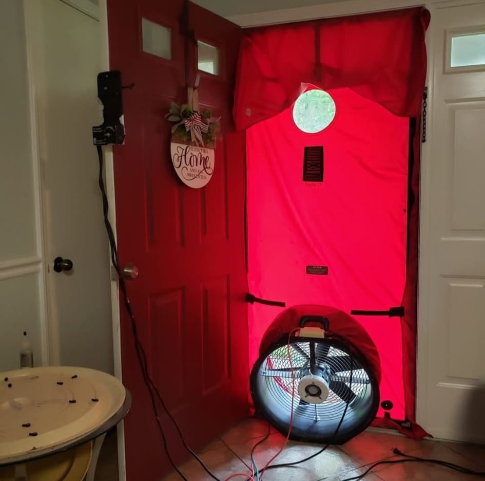 Blower door test setup with red fabric panel covering the front door