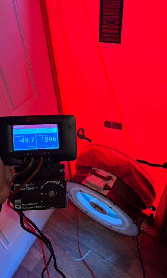 Close-up of blower door test reading -49.7 Pa and 1896 CFM measurements